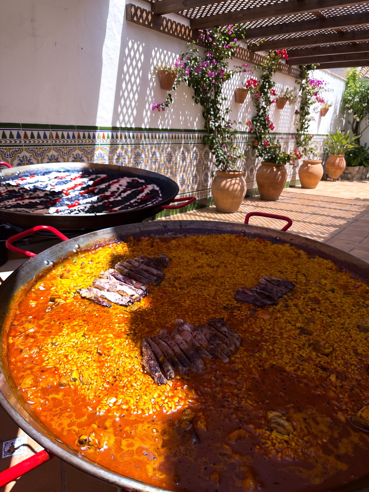 Dos paelleras cocinando en un patio andaluz