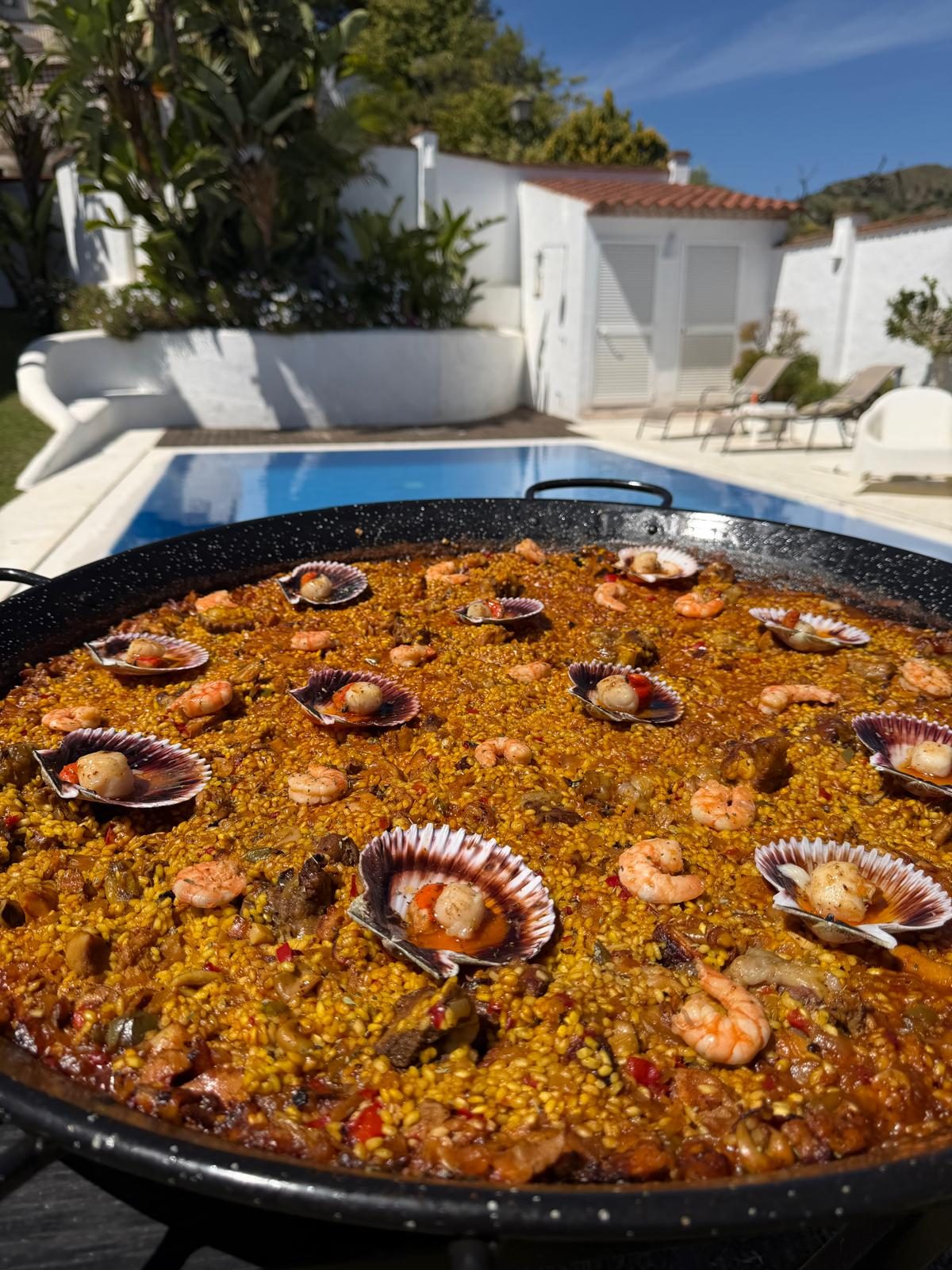 Paella de marisco recién hecha junto a una piscina